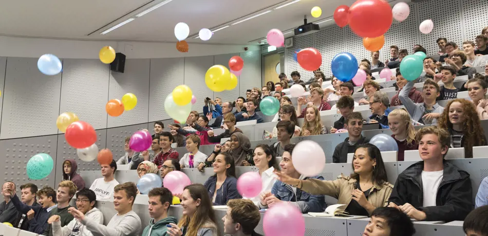 Lecture theatre of people throwing balloons into the air, at open day 2017