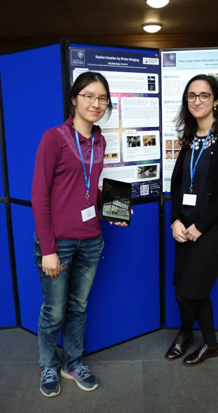 Two researchers pose in front of a poster board at Oxford's Department of Engineering Sciences