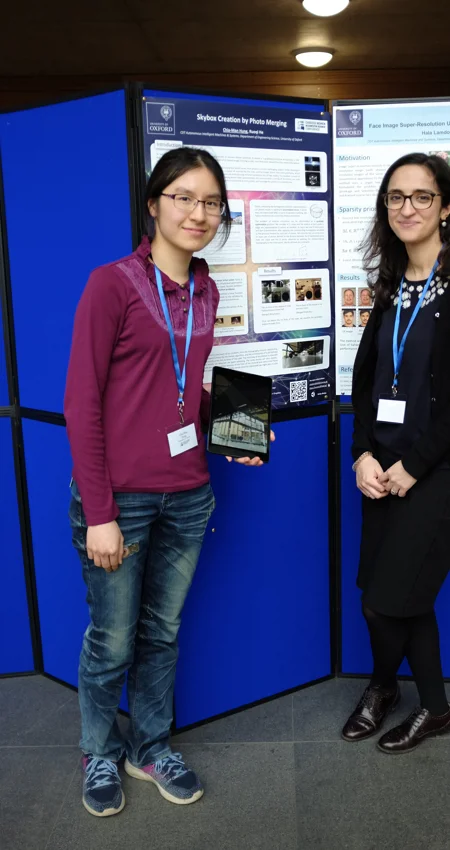 Two researchers pose in front of a poster board at Oxford's Department of Engineering Sciences