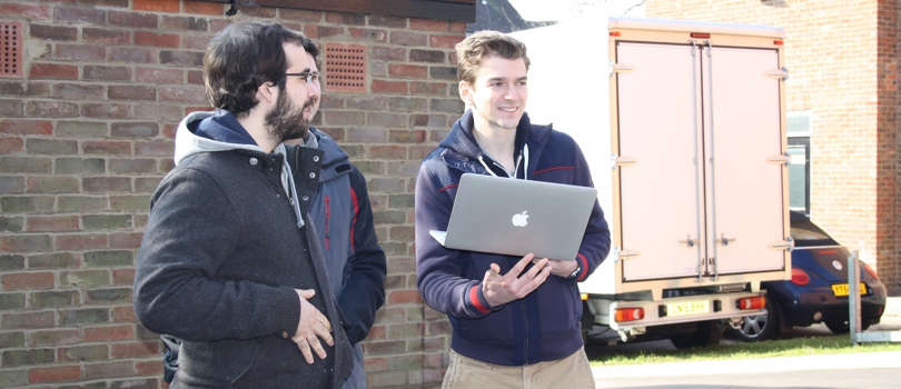 Researchers holding a laptop outside at Oxford's Department of Engineering Sciences