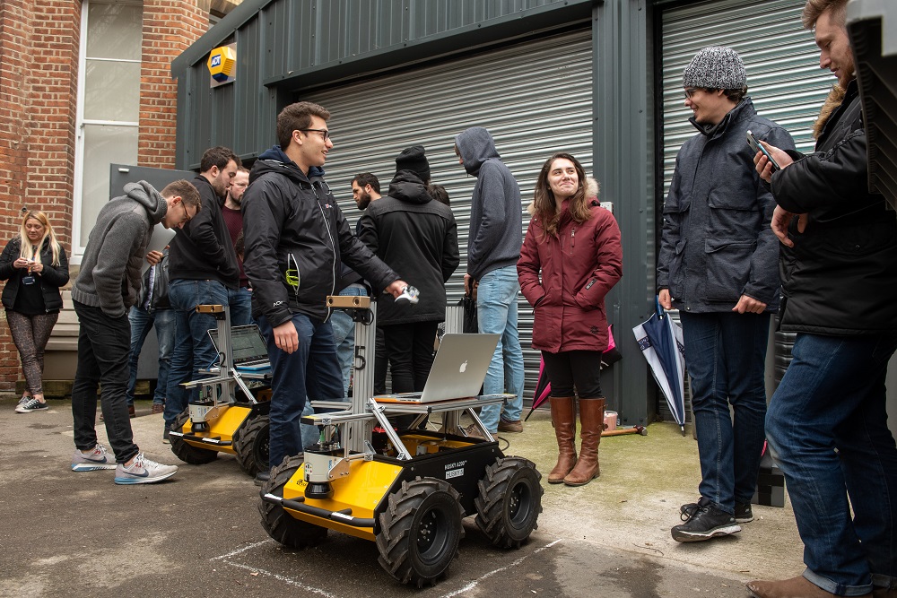 researchers crowd around a robot outside at Oxford's Department of Engineering Sciences