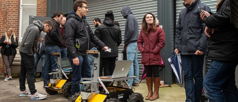 researchers crowd around a robot outside at Oxford's Department of Engineering Sciences