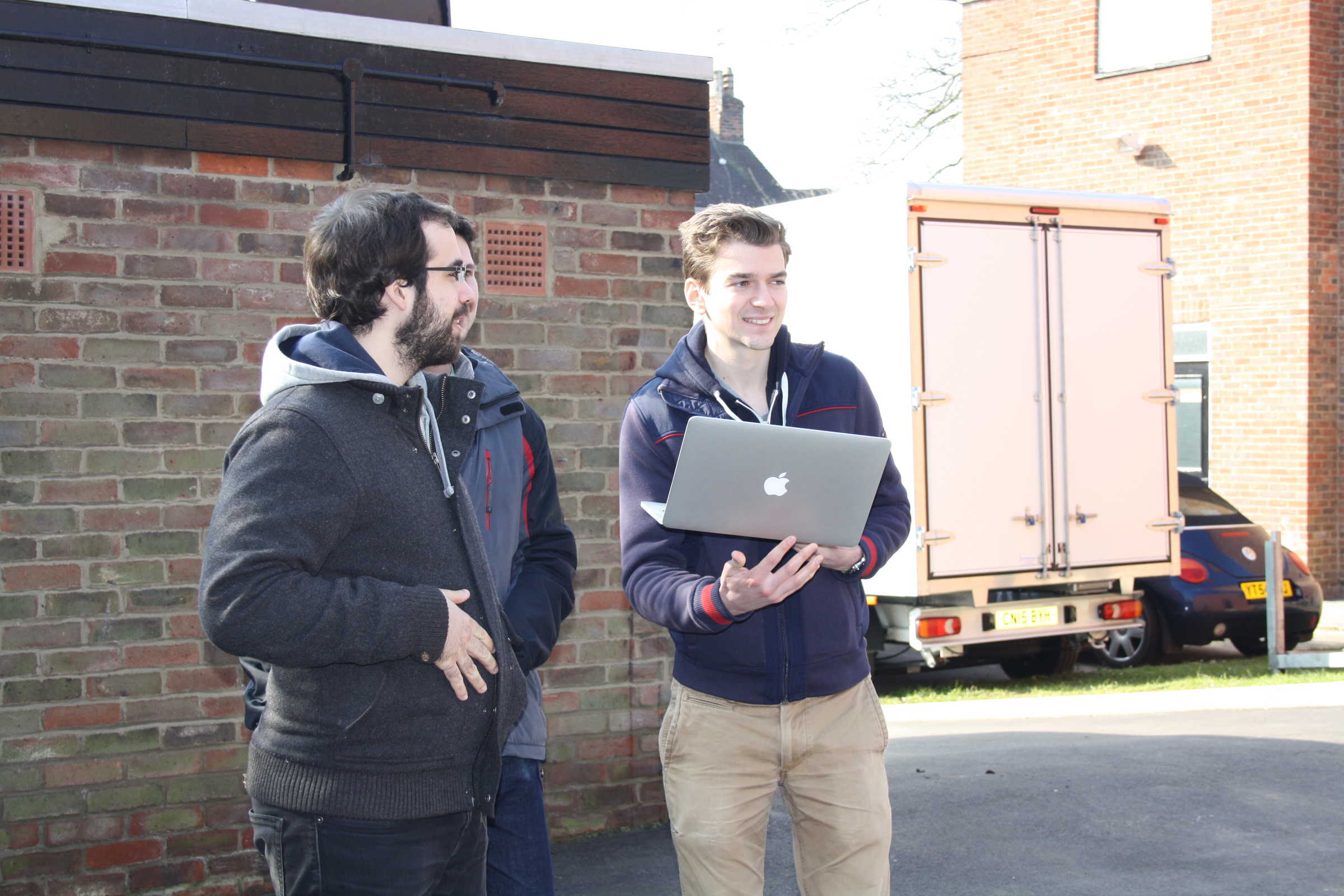 Researchers holding a laptop outside at Oxford's Department of Engineering Sciences