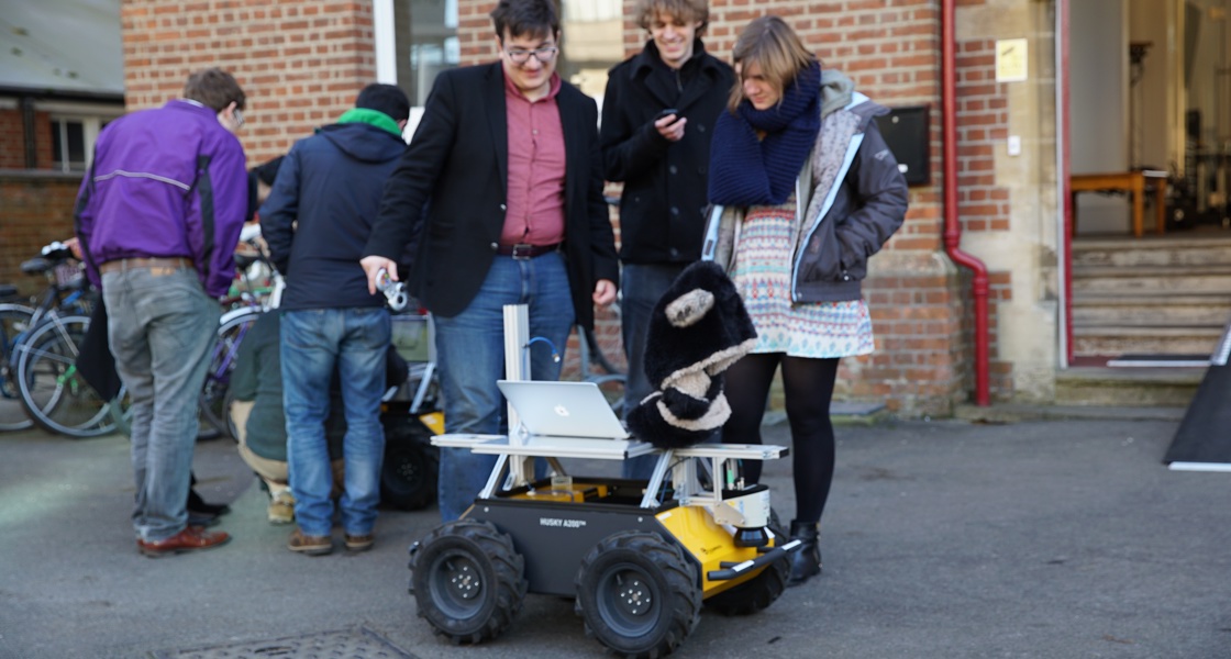 researchers crowd around a robot outside at Oxford's Department of Engineering Sciences