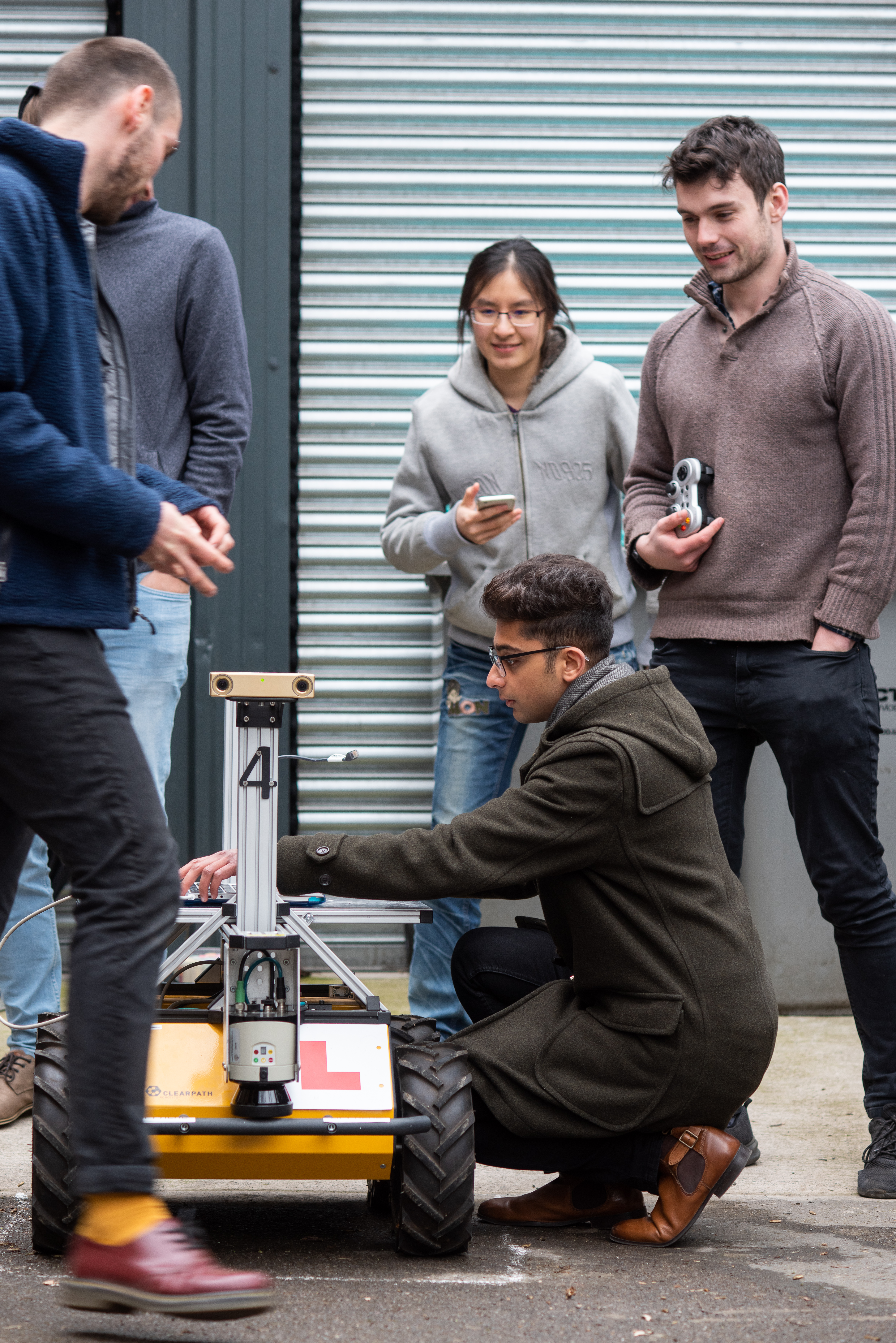 researchers crowd around a robot outside at Oxford's Department of Engineering Sciences